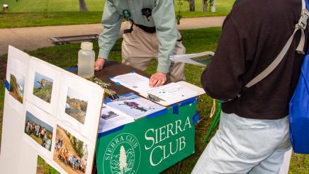 Sierra Club staffer at booth, speaking with attendee