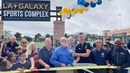 Ceremonial ribbon cutting on stage with giant scissors