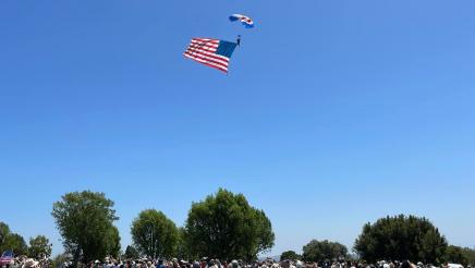 Audience looking up at skydiver with large American flag