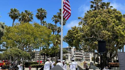 Military members raising the U.S. flag at memorial