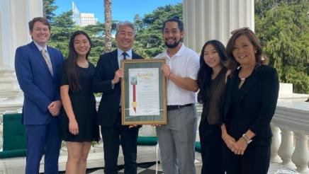 Asm. Muratsuchi on balcony with young South Bay leaders, holding award