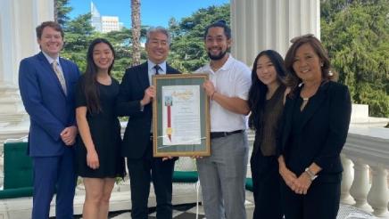 Asm. Muratsuchi on balcony with young South Bay leaders, holding award