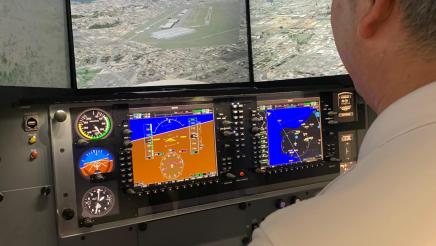 Asm. Muratsuchi seated, using flight simulator