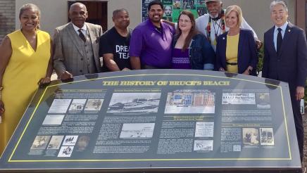 Bruce family and legislators around informational display of beach's history