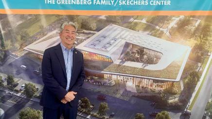 Assemblymember Muratsuchi poses in front of a sign that reads Friendship Campus. 