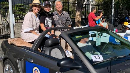 Assemblymember Muratsuchi poses for a photo on a parade float. 