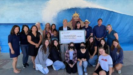 Asm. Muratsuchi, with district staff and students, holding check