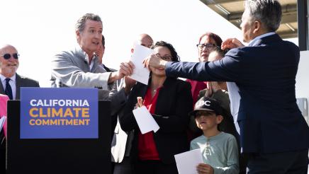 Assemblymember Al Muratsuchi exchanges paper with Governor Gavin Newsom