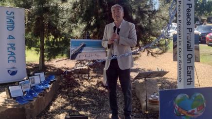 Assemblymember Al Muratsuchi stands with a microphone as he addresses the crowd at the International Day of Peace event. 