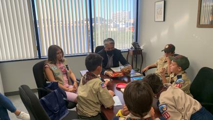 Asm. Muratsuchi sitting at table with scouts, sharing cookies