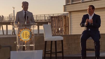 Asm. Muratsuchi at podium, speaking, while Mayor Mike Detoy applauds