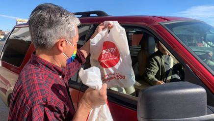 Asm. Muratsuchi distributing food bags to constituent in car