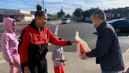 Asm. Muratsuchi handing food bag to mother with kids
