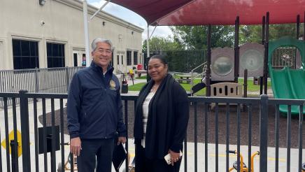 Asm. Muratsuchi and Jennifer Carter in front of outdoor play area for kids