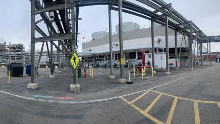 Wide photo of Asm. Muratsuchi and tour guide observing machinery outside