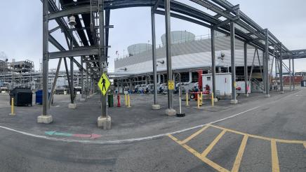 Wide photo of Asm. Muratsuchi and tour guide observing machinery outside