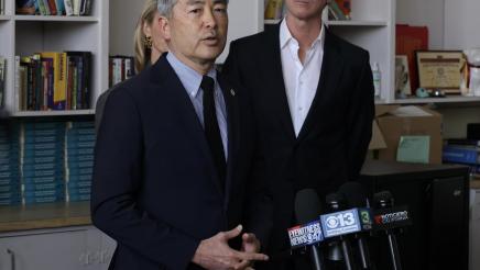 Asm. Muratsuchi at microphones, speaking, with Gov. Newsom listening on