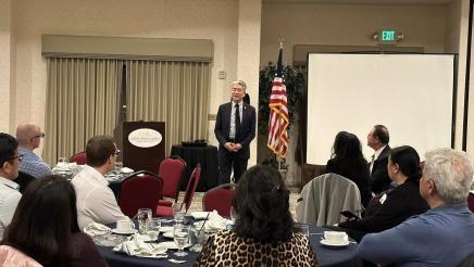 Asm. Muratsuchi standing, speaking to attendees at tables