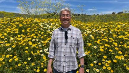 Asm. Muratsuchi with field of flowers in background