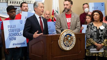 Asm. Muratsuchi at podium, speaking, as Pres. Jeff Freitas listens on