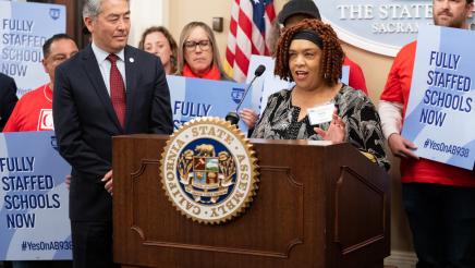 CTA Board Member Shelly Gupton at podium, speaking, as Asm. Muratsuchi listens on