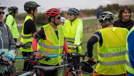 Participants in florescent yellow vests listening on
