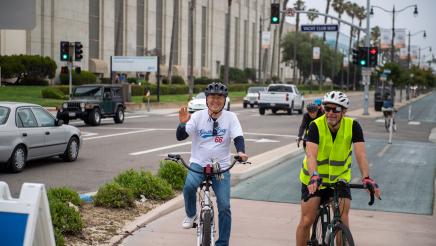 Asm. Muratsuchi on bike, waving to constituents
