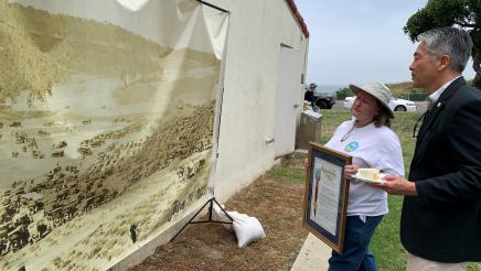 Asm. Muratsuchi and constituent viewing banner of vintage 1923 photo of multiple cars gathered