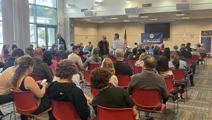 Wide view of many attendees, seated in large room