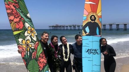 Group photo of surfer participants with two upright surfboards