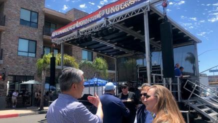 Asm. Muratsuchi speaks with two constituents, with stage in background