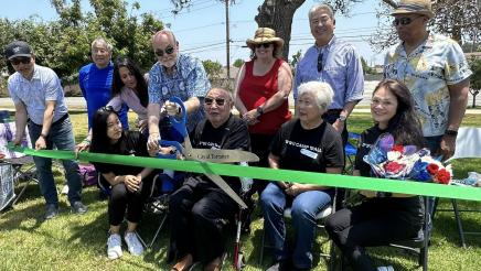 Senior helping to cut ceremonial ribbon with large scissors