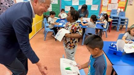 Young student handing Asm. Muratsuchi a drawing