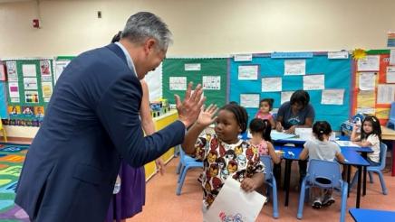 Asm. Muratsuchi bends down to high-five a student