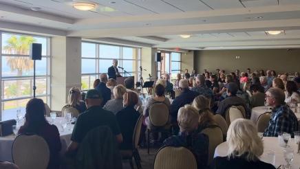 Asm. Muratsuchi at podium, speaking, while many audience members listen on