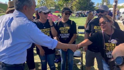 Asm. Muratsuchi shaking hands with striking healthcare worker as other striking healthcare workers look on