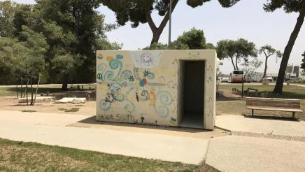 Small, freestanding concrete bomb shelter covered with children's art