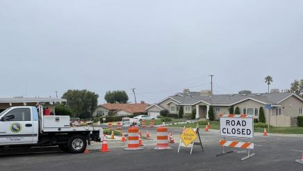 Traffic safety cones and drums and Road Closed and Rough Road signs blocking streets