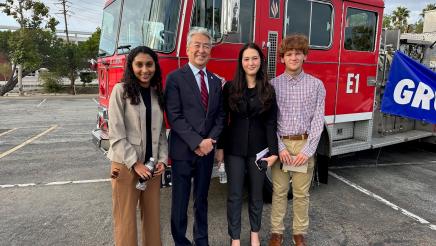 Asm. Muratsuchi standing with students, with fire engine in background