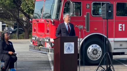 Asm. Muratsuchi at podium, speaking, with fire engine in background