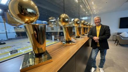 Asm. Muratsuchi standing with multiple Lakers championship trophies