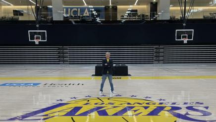 Asm. Muratsuchi standing in middle of basketball court with Lakers logo at center
