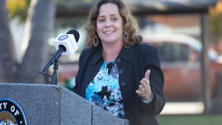 Guest speaker at podium, speaking and gesturing to the side