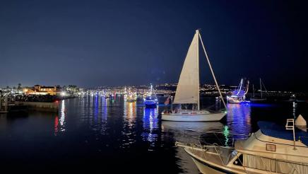 Boats on the water at night, with illuminated shoreline in distance