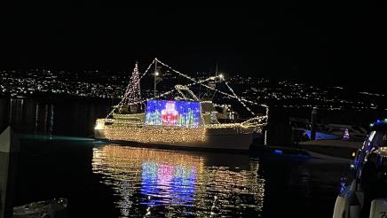 Boats on the water at night featuring Christmas lights and decorations