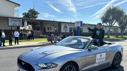 Asm. Muratsuchi sitting high in back of parade car, waving to constituents