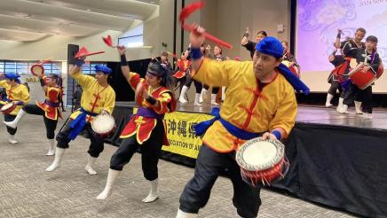 Performers, some with drums, onstage and in front of stage