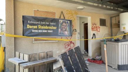 Roped off home with banner in front depicting kidnapping victim