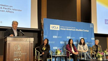 Asm. Muratsuchi onstage at podium, speaking, while other panelists listen on