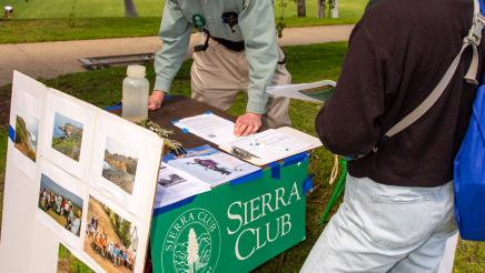 Sierra Club staffer at booth, speaking with attendee